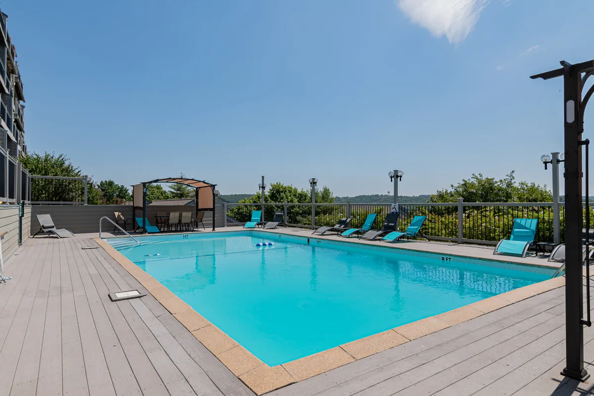 A sparkling outdoor swimming pool surrounded by lounge chairs and a covered canopy area. The space is inviting and perfect for family relaxation, socializing, and sunbathing during the warmer months.