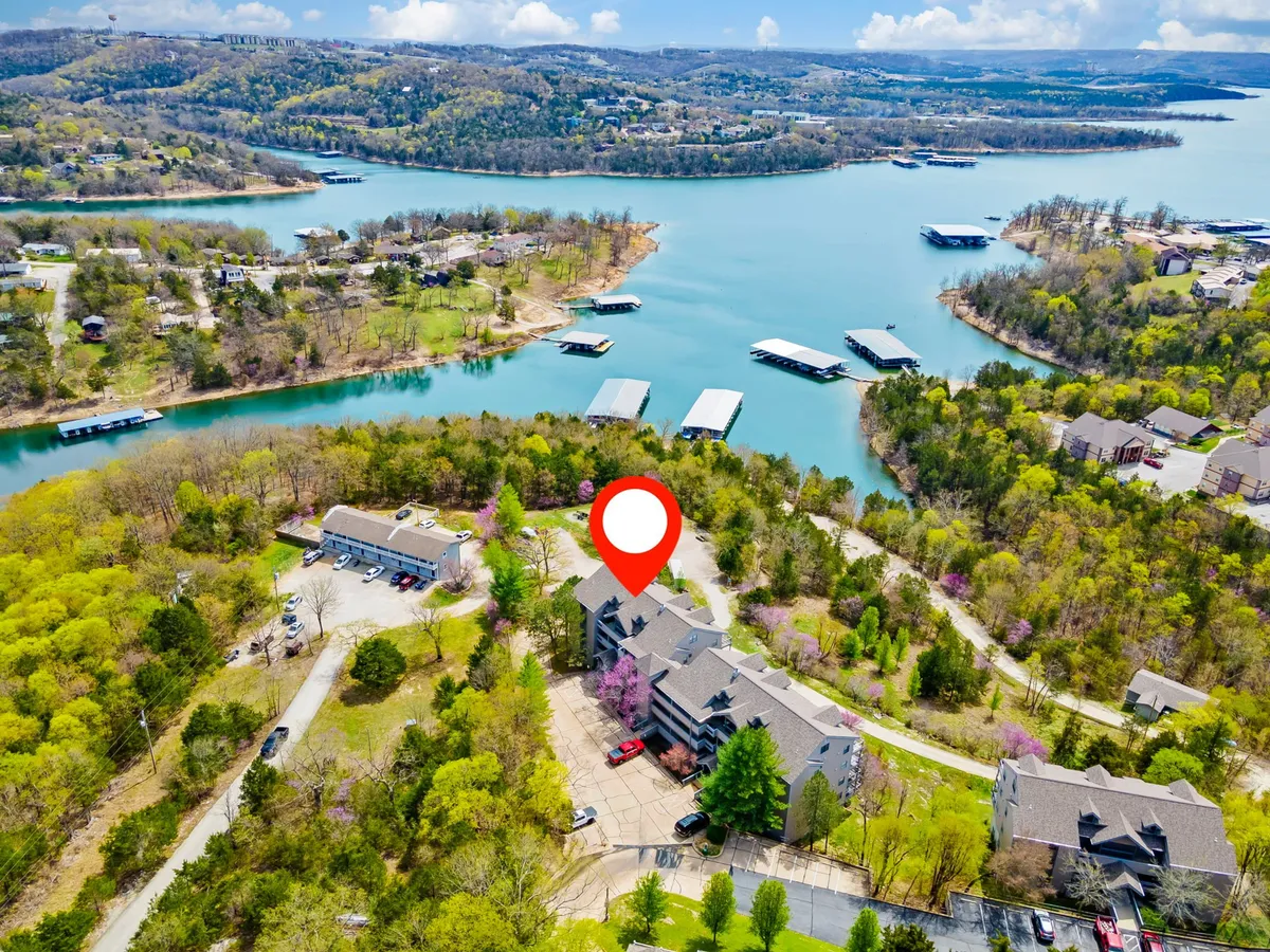 A sweeping aerial view of a large, tranquil lake bordered by lush greenery, residential buildings, and a marina filled with boats. The scene highlights opportunities for boating, fishing, and water sports, with the sun setting over the water to create a relaxed, adventurous mood.