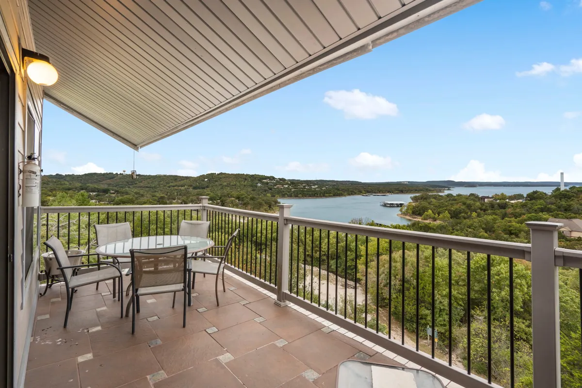 A serene outdoor dining area overlooking Table Rock Lake, surrounded by lush greenery. The spacious table is set up for al fresco dining and gathering, with a backdrop of tranquil water and distant trees. The scene evokes togetherness in a natural setting, perfect for family picnics or evening gatherings under the sky.