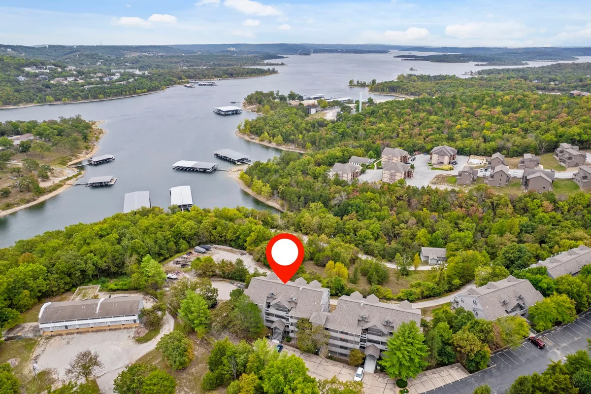 A scenic view over Table Rock Lake with calm waters, lush greenery along the shoreline, boats docked at the marina, and buildings in the background. The image conveys a peaceful setting ideal for water activities and lakeside relaxation.