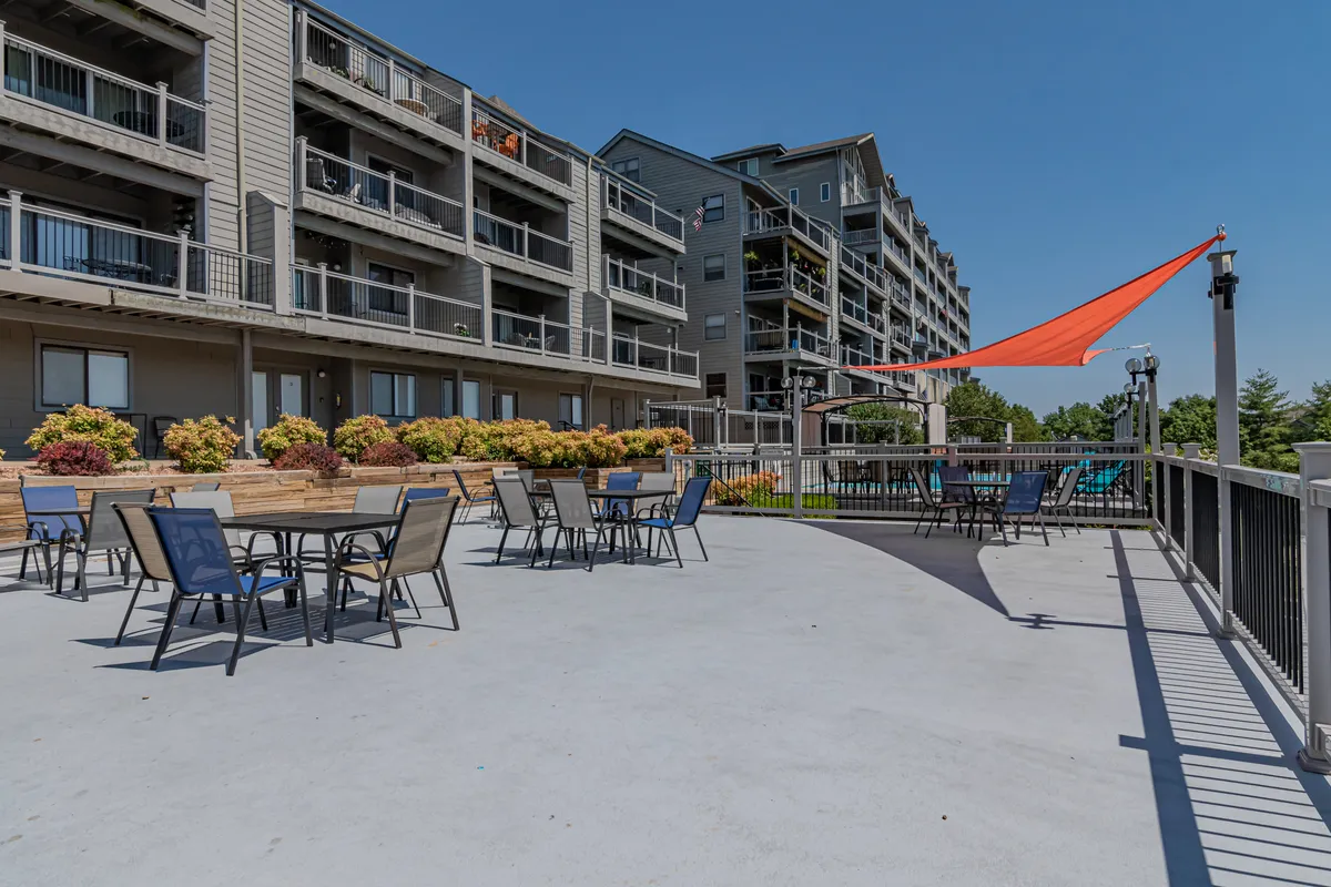 An outdoor seating area adorned with colorful flowers and a shade sail, offering a comfortable place to relax, socialize, or enjoy the outdoors. The terrace looks out over natural surroundings, suggesting a seamless connection between indoor comfort and outdoor beauty.