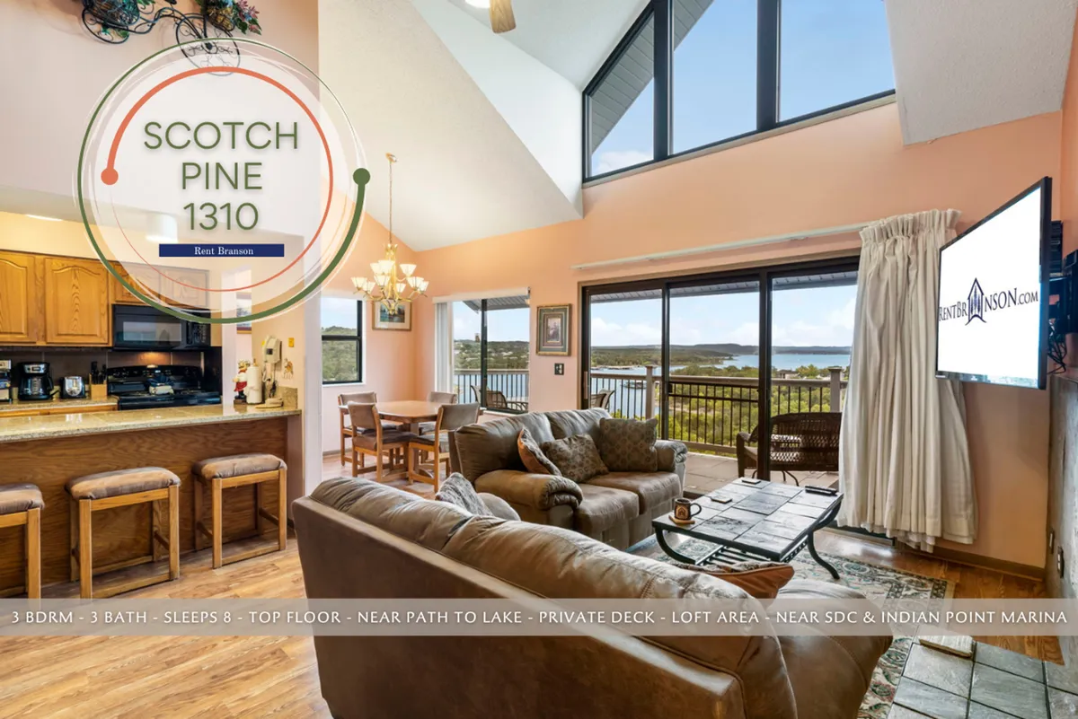 This image showcases a spacious, open living area with large windows offering a captivating lake view, a well-equipped kitchen with updated finishes, and a cozy seating arrangement ideal for gatherings. The seamless transition between the kitchen and living space is evident, inviting natural light and fostering a warm, social environment.