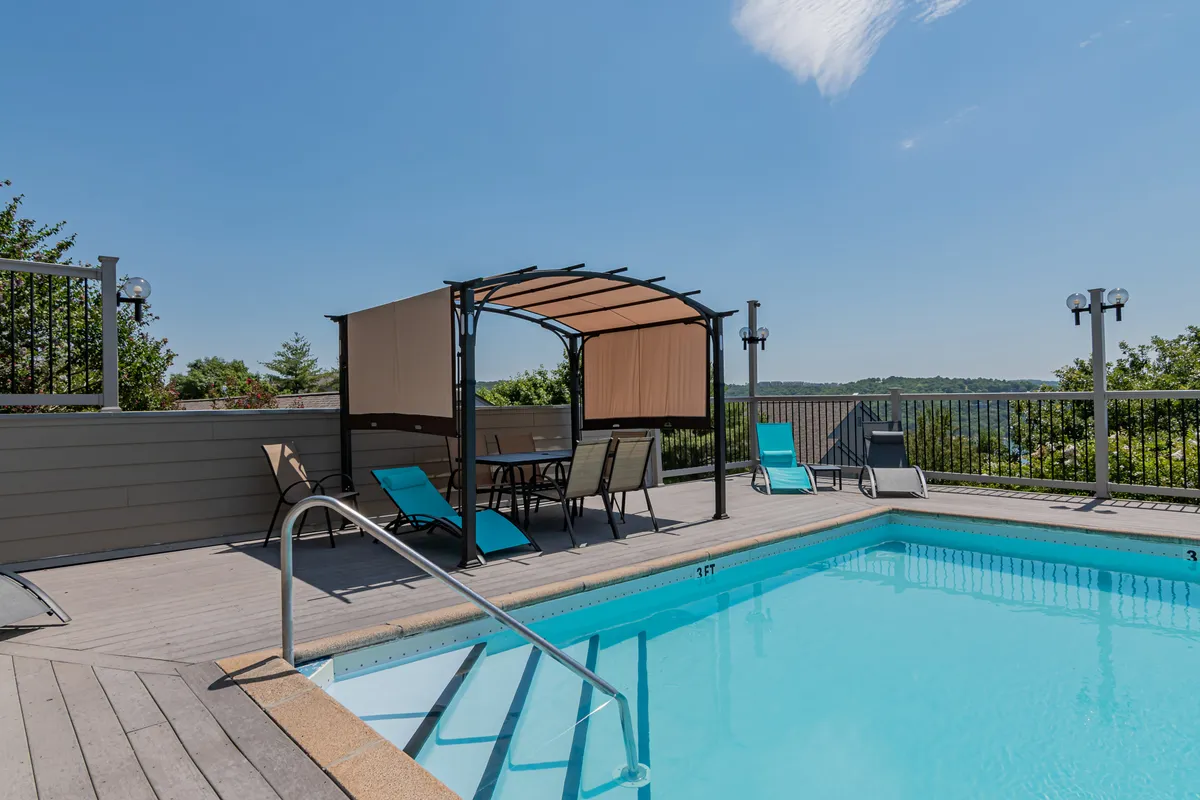 A tranquil outdoor pool area with lounge chairs, a shaded canopy seating area, and scenic views beyond. The atmosphere is serene, perfect for sunbathing, swimming, or socializing after a day of exploration.