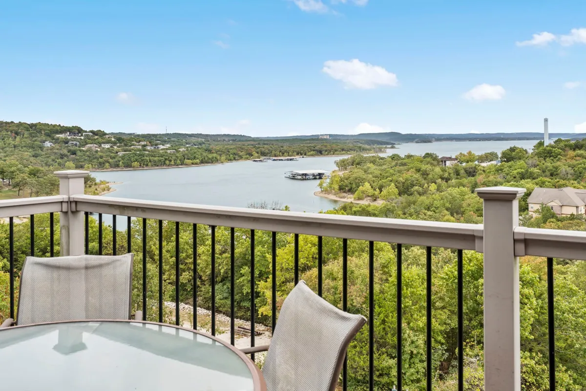 The image showcases a peaceful balcony overlooking Table Rock Lake, surrounded by lush greenery. Comfortable outdoor furniture invites guests to relax, enjoy a book, sip morning coffee, or take in the sunrise. The setting promises tranquility, starry nights, and the chance to spot local wildlife.