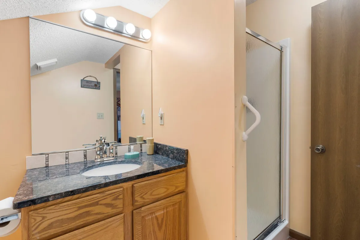 A well-lit bathroom showcasing a spacious sink, large mirror, and a glass shower stall. The space is modern, clean, and inviting, reflecting updated finishes and a fresh atmosphere.